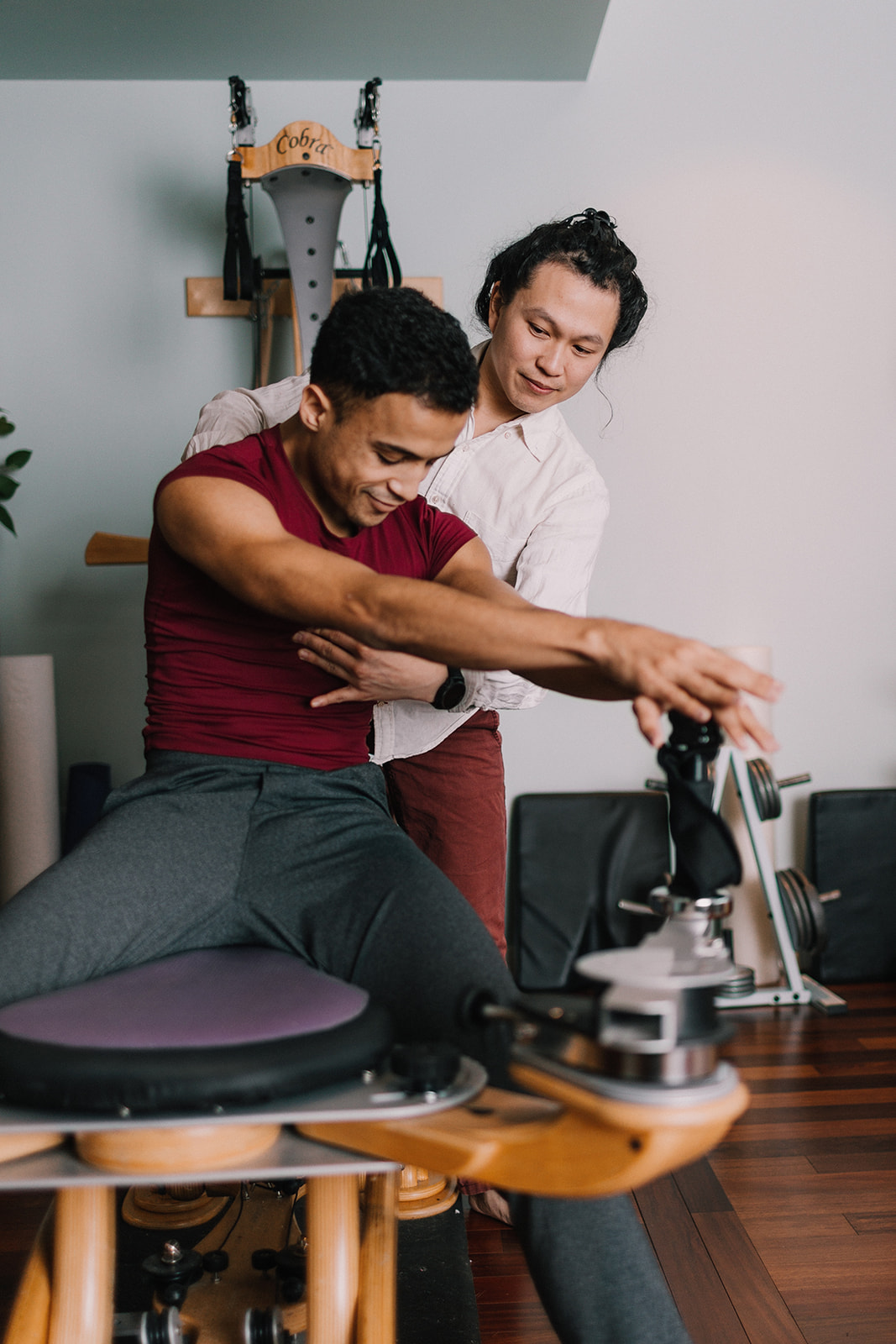 Gyrotonic Trainer Joseph Liu guiding a student on the Gyrotonic Pulley Tower Machine